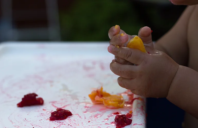 Close up of a baby's hands holding a fresh orange.