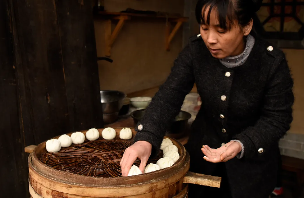 A Chinese woman is seen making Baozi in a small street stall on April 10, 2017 in Yuanjiacun, China.