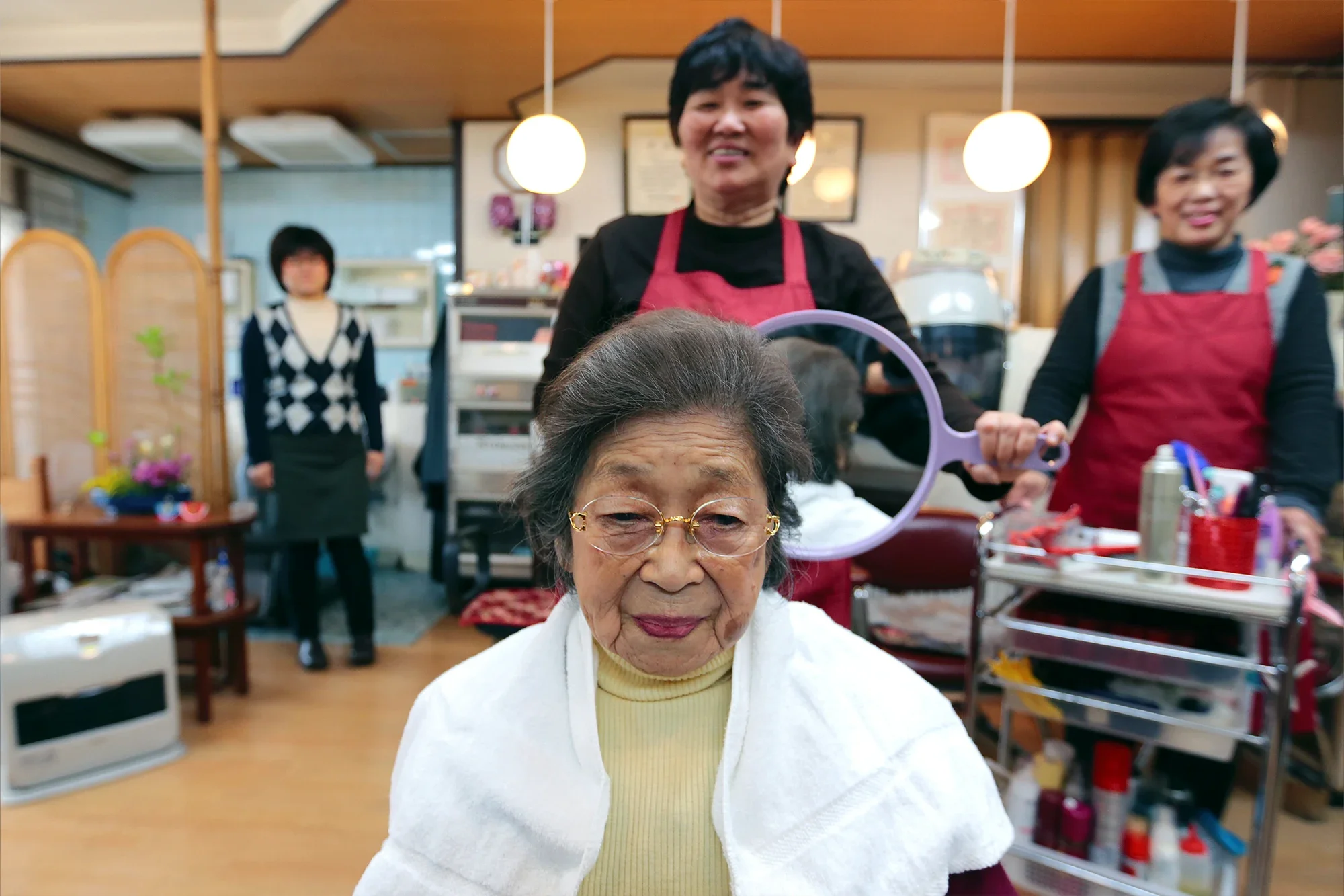 Masa Narita, a centenarian, gets her hair set by a hairdresser at a beauty salon near her house in Osaka, Japan.
