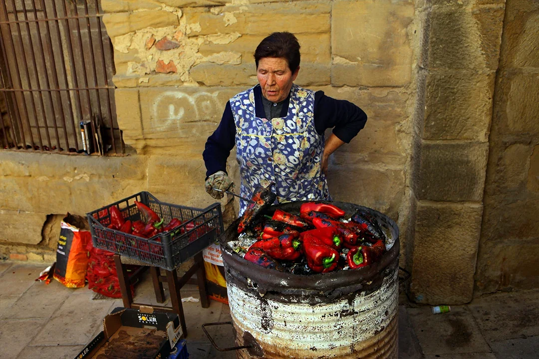 A Spanish woman maintains a centuries-old tradition of roasting sweet peppers over an open fire to preserve the fruit